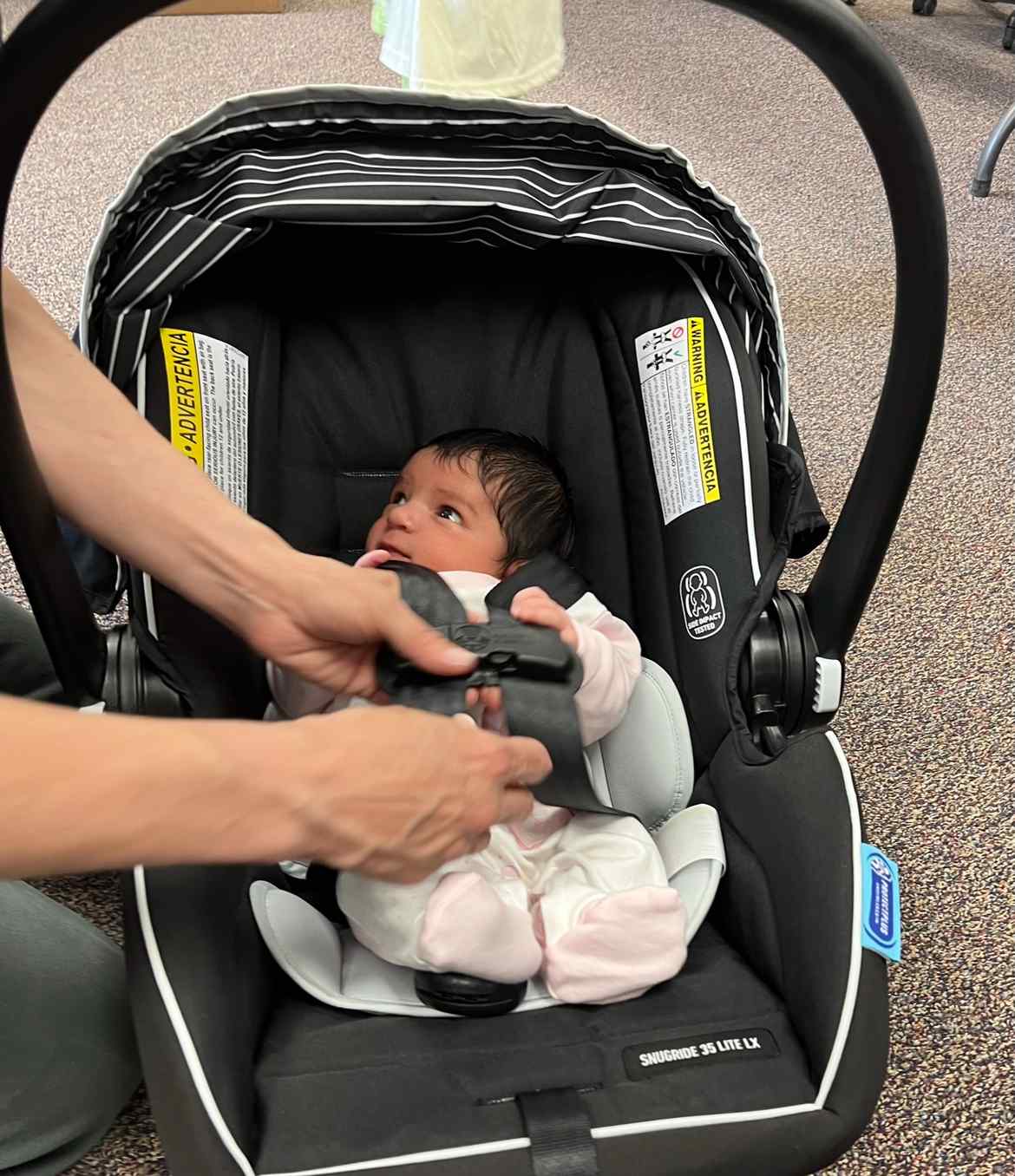 A refugee infant is carefully buckled into a new car seat while receiving hands-on guidance, showing how Utah Refugee Connection combines safety education with practical support for refugee families in Utah.