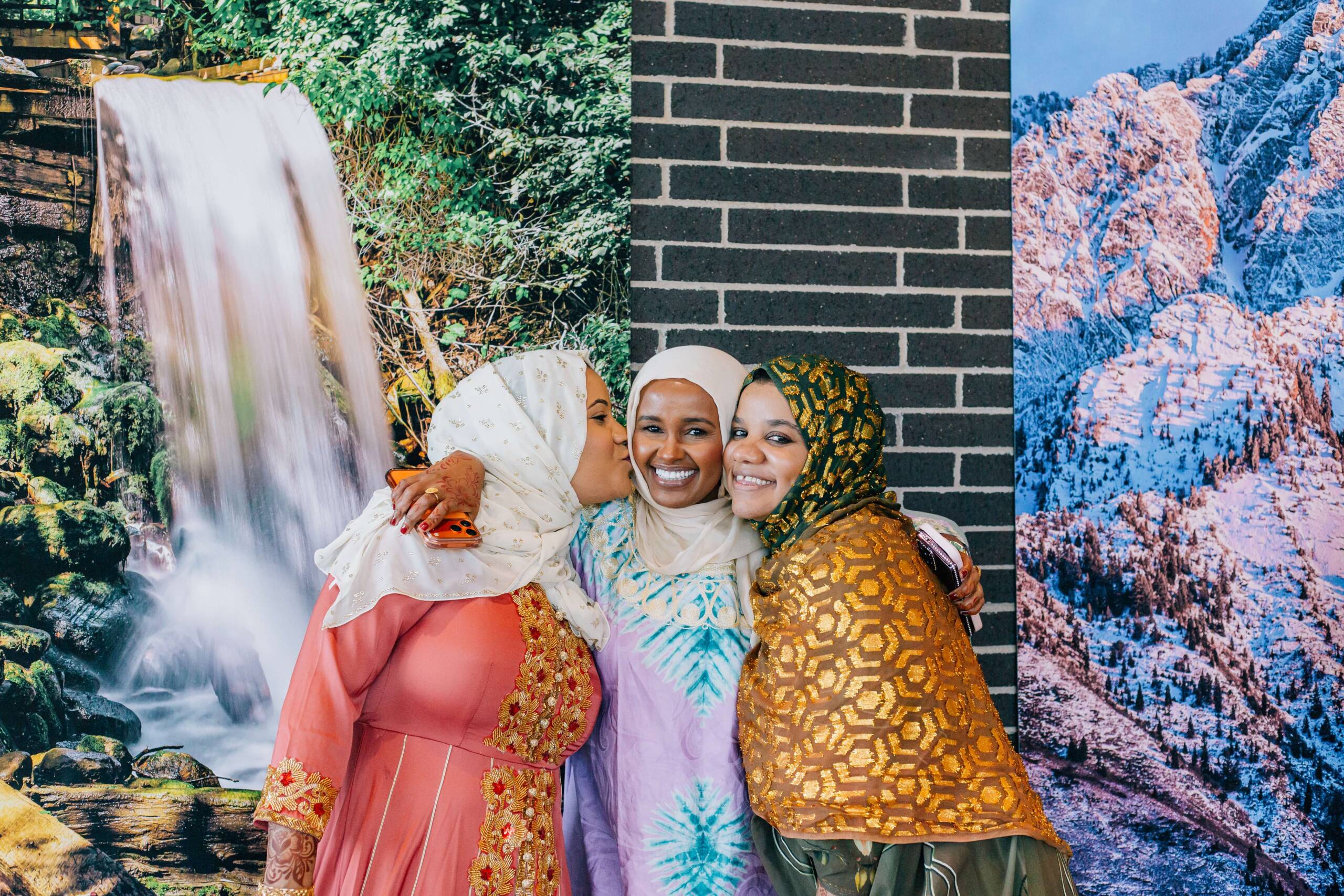 Three women smile and embrace during Utah Refugee Connection’s International Women’s Day event. The celebration brought women together through friendship, culture, and a shared sense of belonging and support.